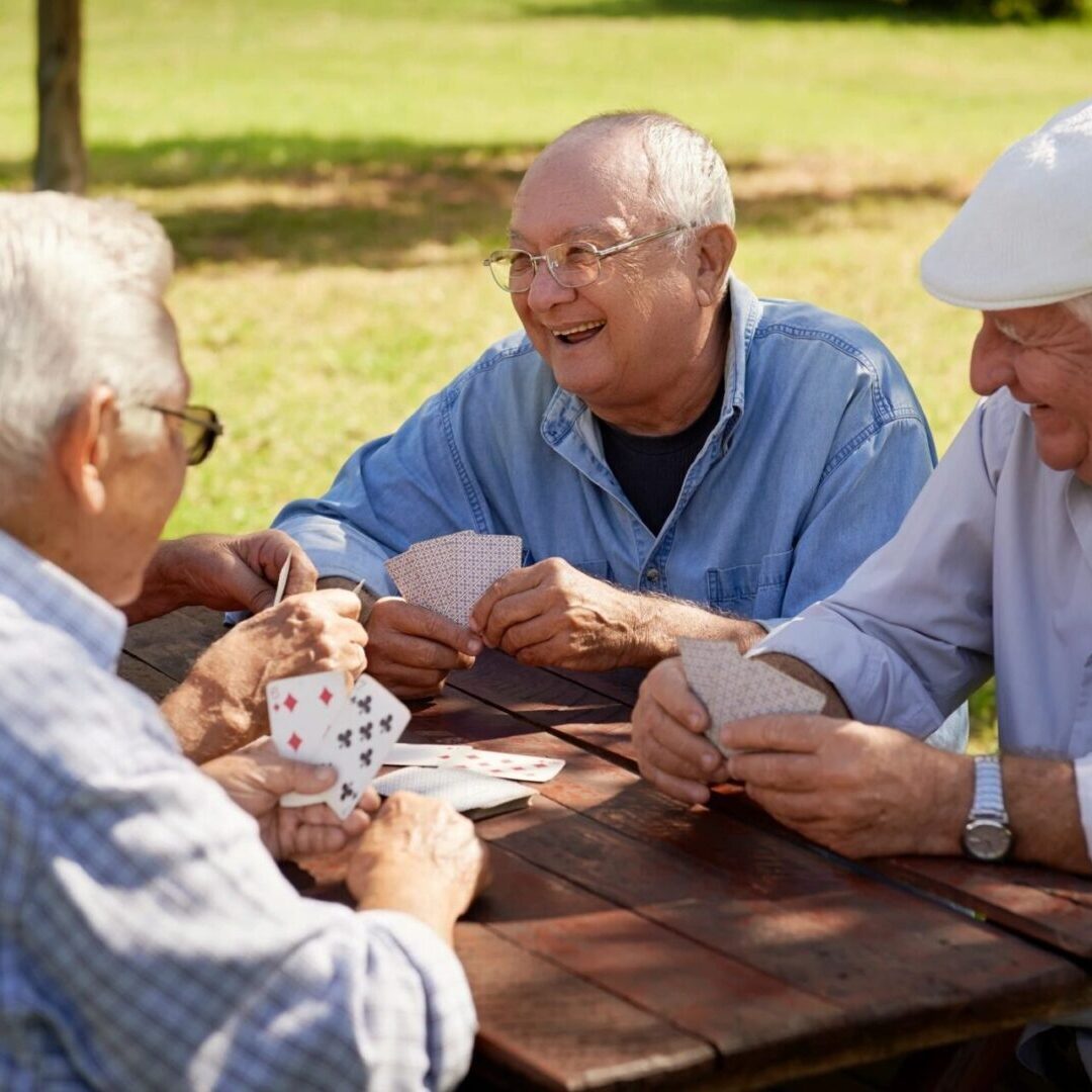 Three older men sitting at a table playing cards.